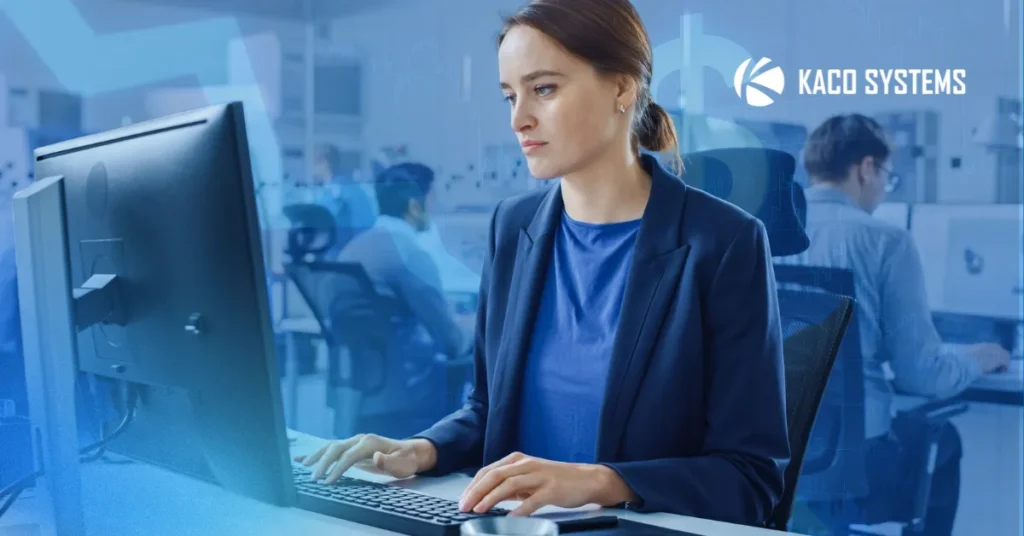 An image that represents the blog title: The Hidden Cost of an IT Provider Who Never Pushes Back. A woman is sitting at the computer, in a black blazer and blue shirt, looking concerned. You can see a busy office behind her.
