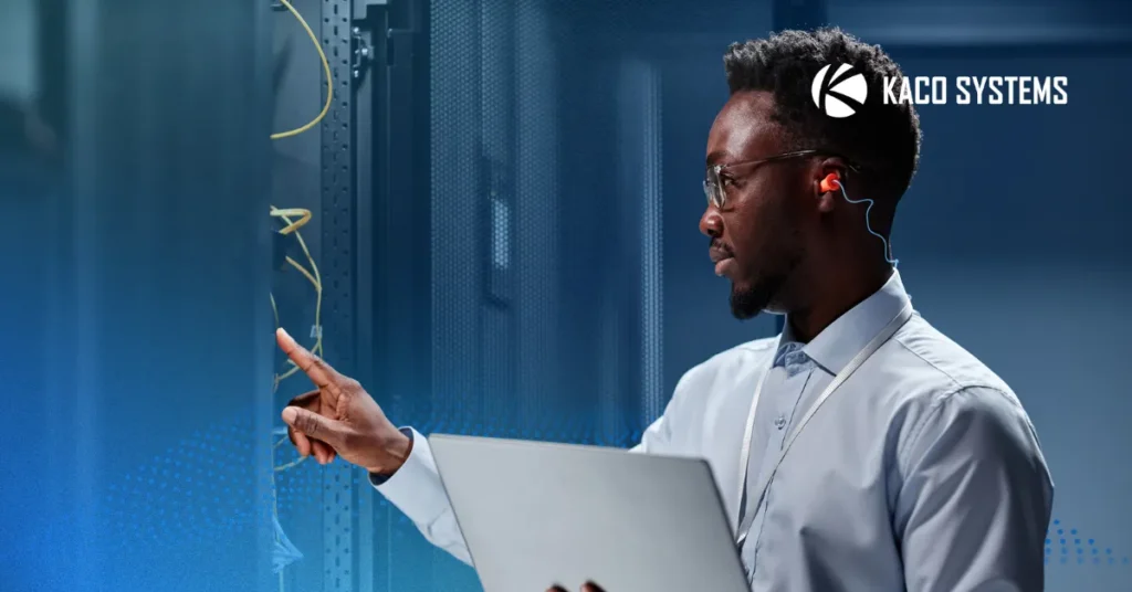 An image to represent the theme and the title of the blog "Five Signs Your IT Provider May Be Overlooking Your Network." There is a man standing in a sever room, touching a machine, while holding a stack of papers, clearly in support mode.